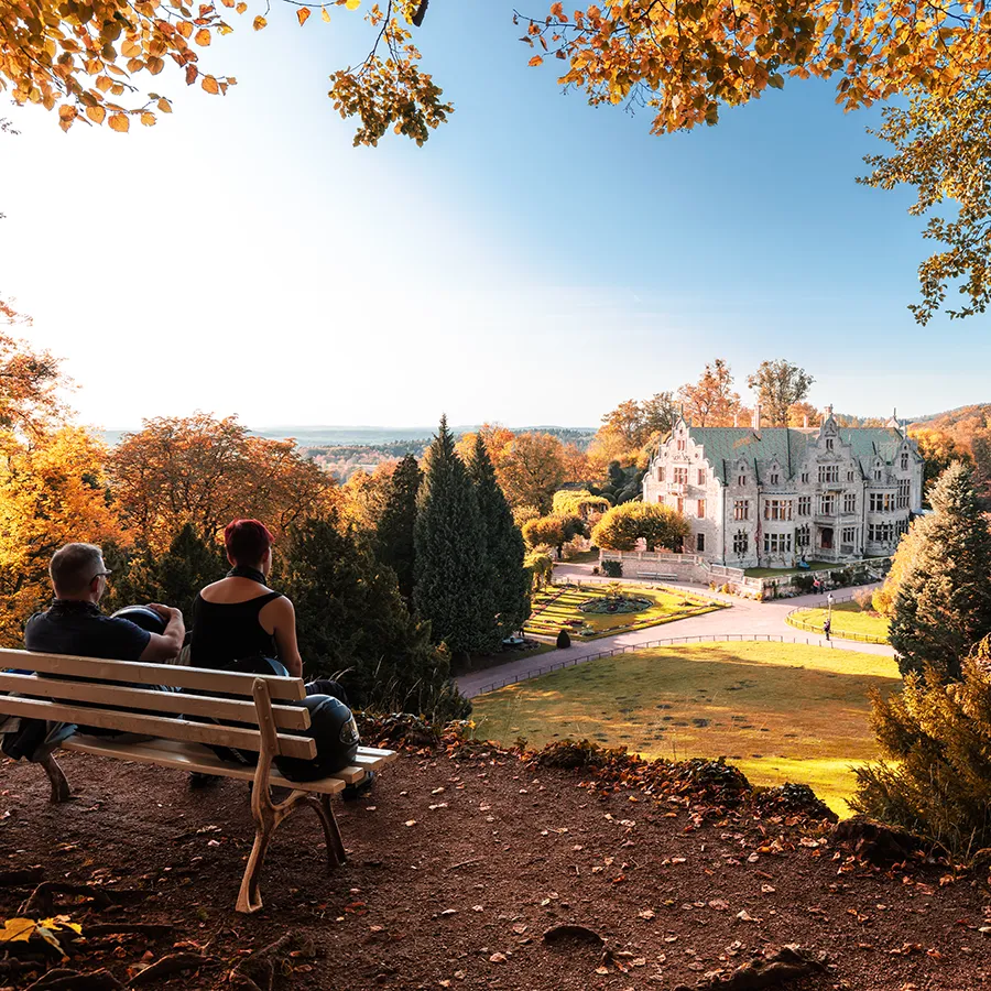 Ein Paar sitzt auf einer Bank mit Blick auf das Schloss Altenstein